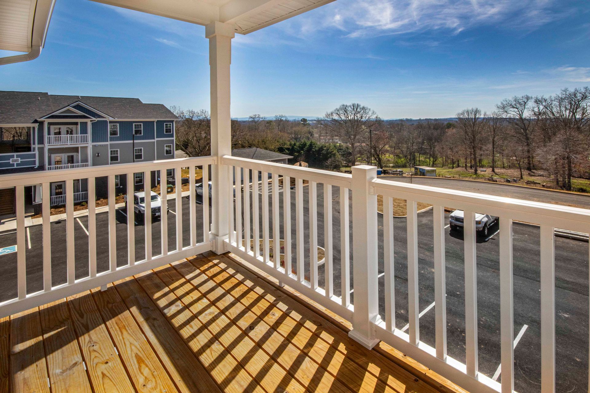 A balcony with a white railing and a view of a house.