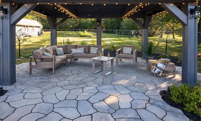 Un patio avec un canapé et des chaises sous un gazebo.