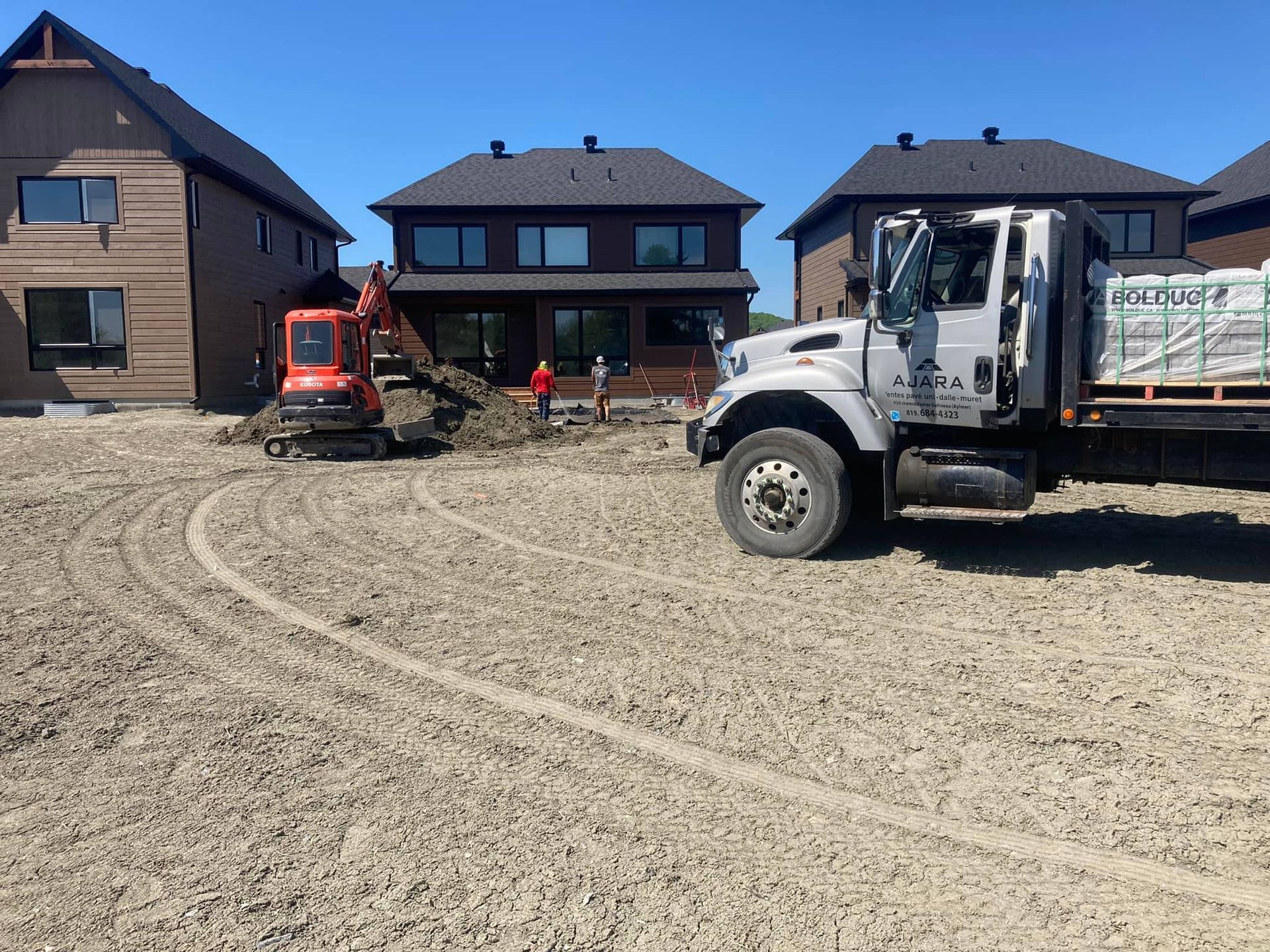 A truck is parked in a dirt field in front of a house.