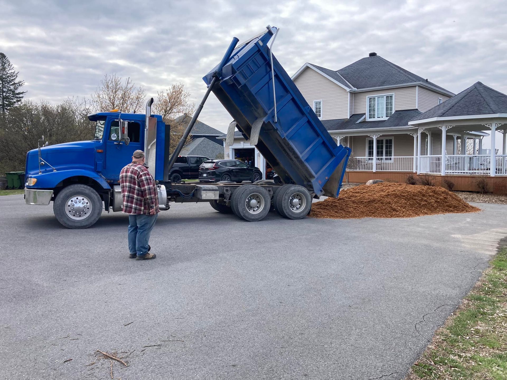 A man is standing in front of a blue dump truck.