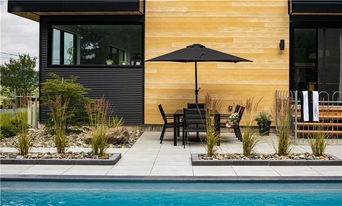 Un patio avec une table, des chaises et un parasol à côté d'une piscine.