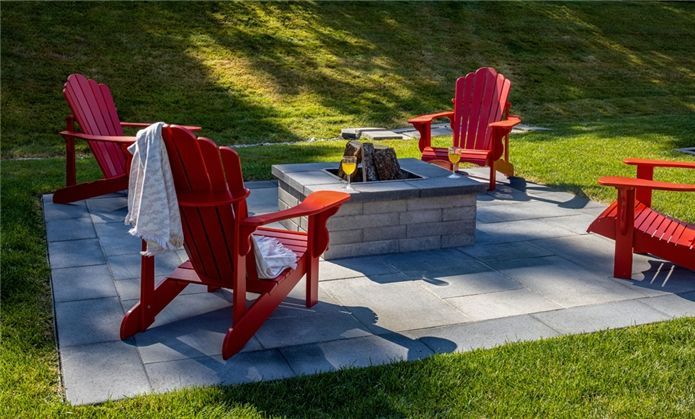 Un foyer entouré de chaises Adirondack rouges dans une cour arrière.