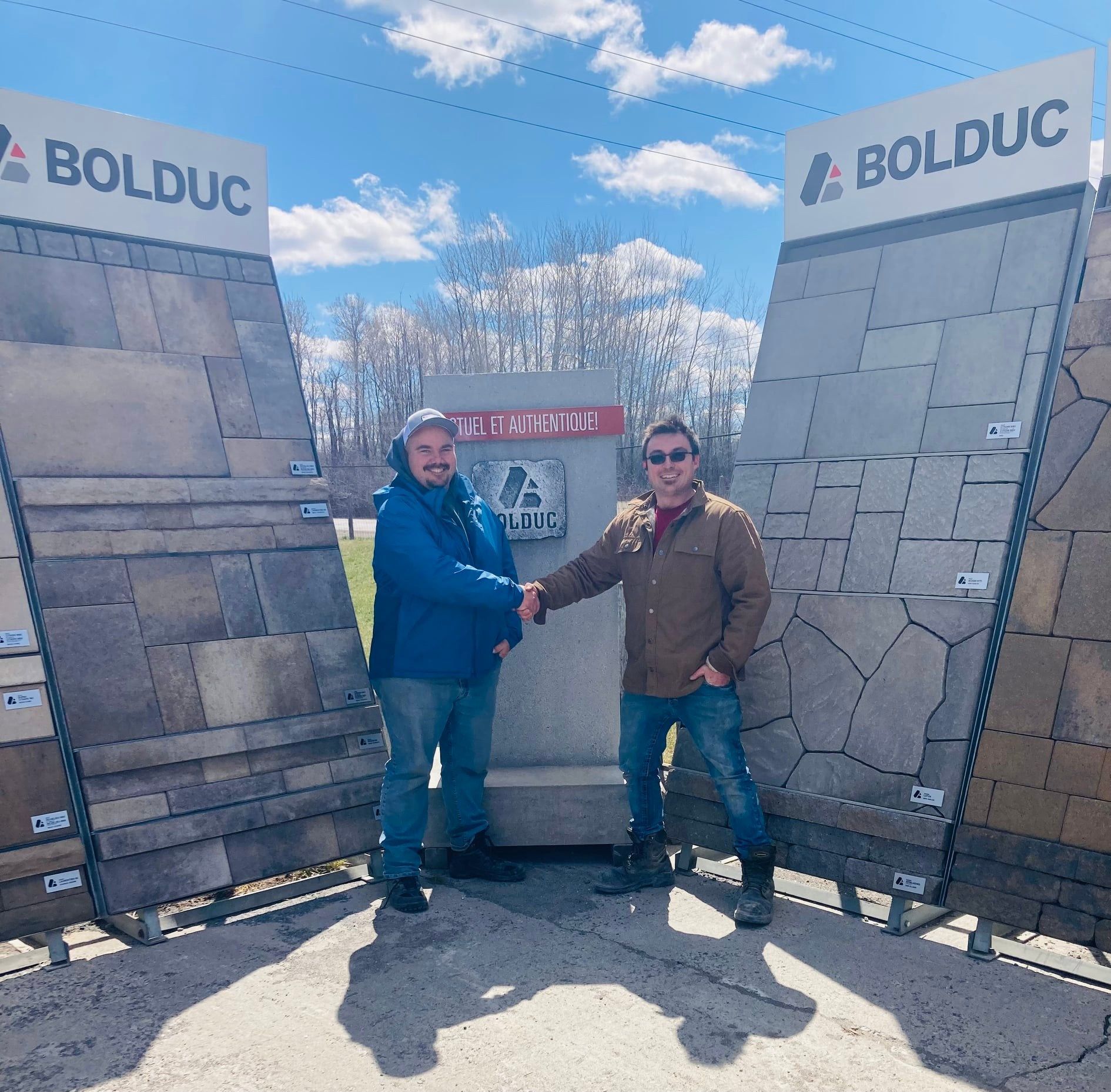 Two men shaking hands in front of a bolduc sign