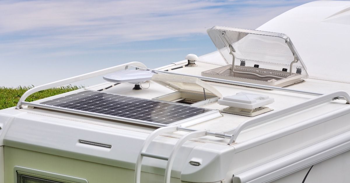 Close-up of an RV rooftop featuring solar panels, ventilation units, and open hatches that affect height clearance.