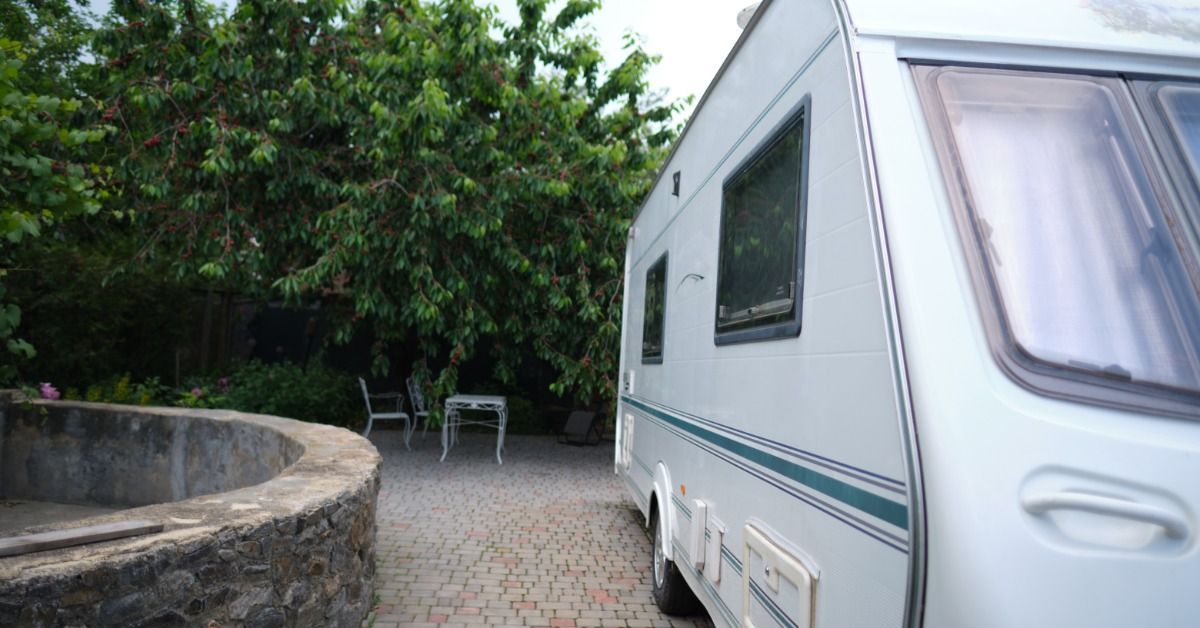 A white RV is parked in a narrow residential driveway where limited space may affect pickup and delivery access.