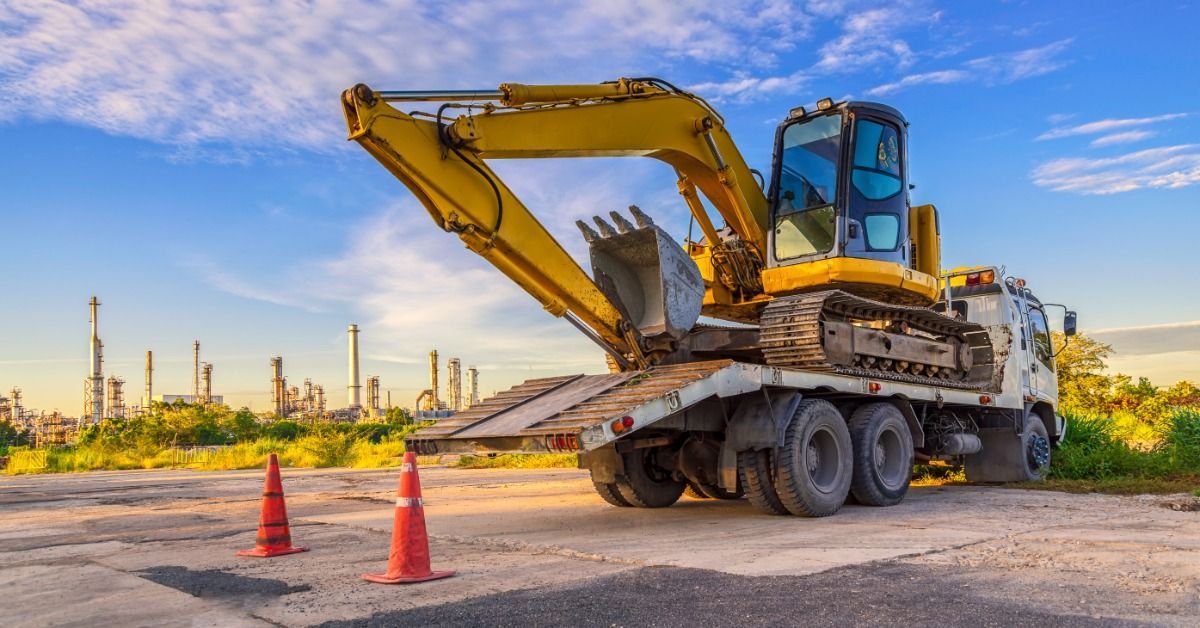 An excavator sits on a transport trailer with open space around the vehicle for equipment unloading and unloading.