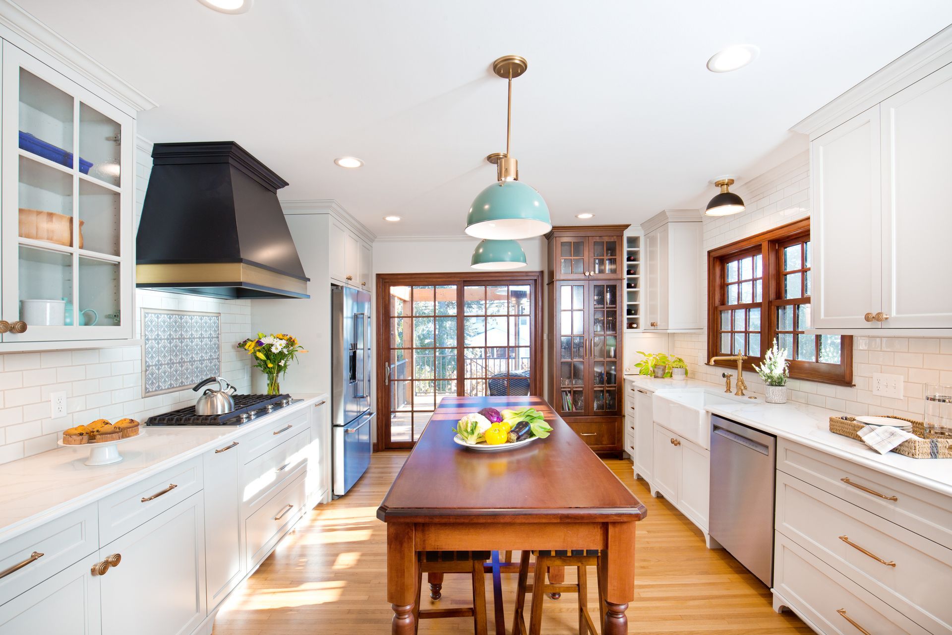 Modern kitchen with white cabinets, wood island, and stainless steel appliances.