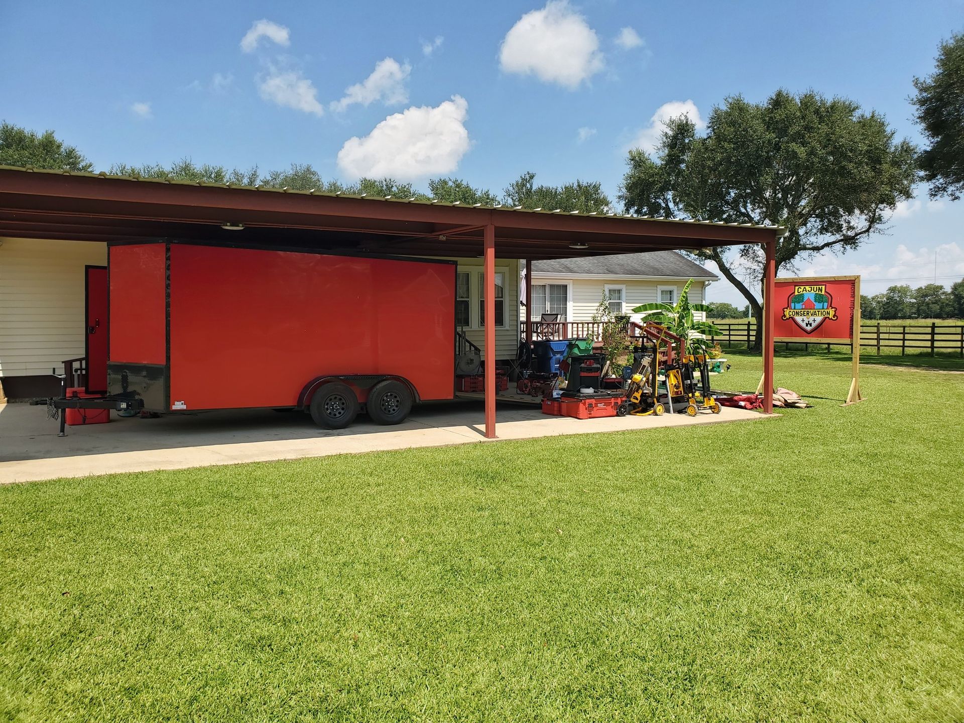 Red concession trailer beside farm equipment on a grassy field under a partly cloudy sky