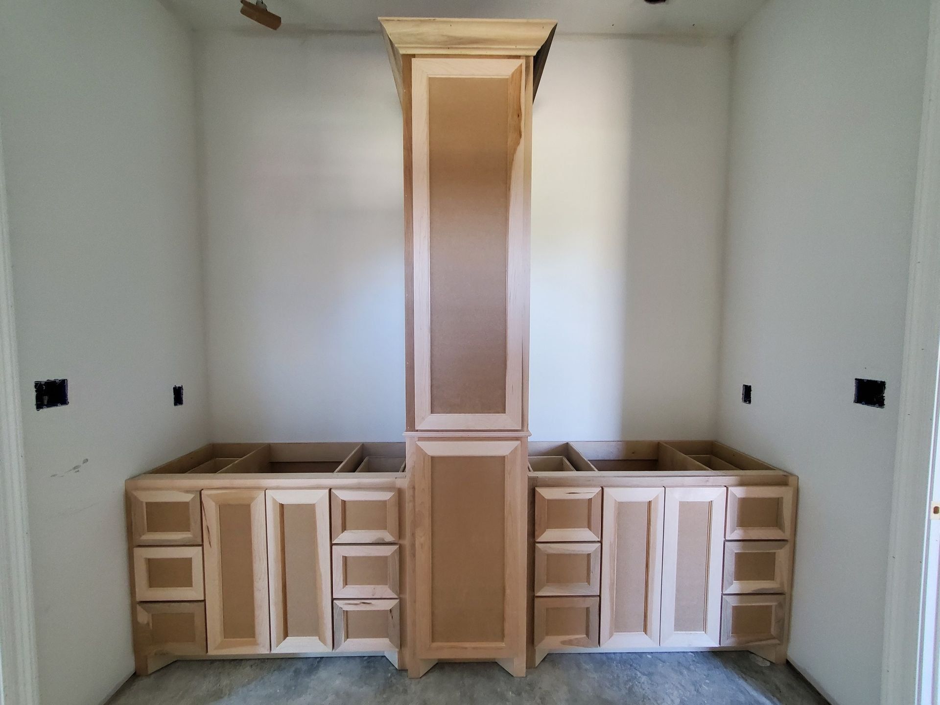 Unfinished kitchen with white cabinets, wood countertops, and a tall central vent hood area.