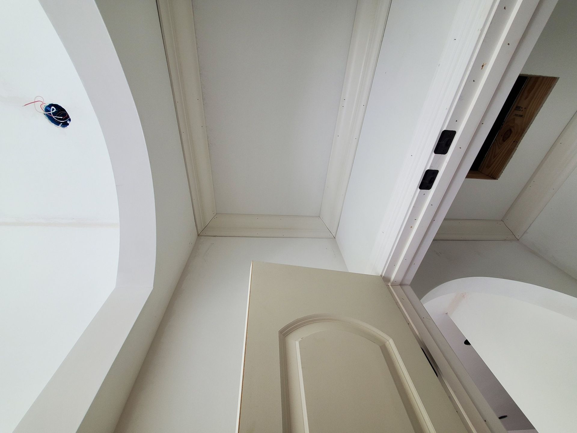Open beige door beneath a white arched ceiling in a bright hallway