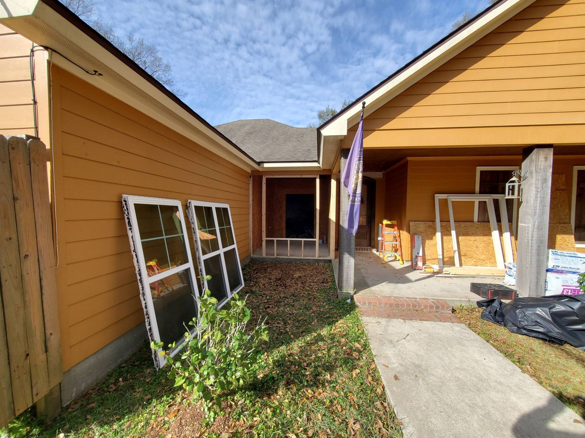 Courtyard between two orange houses with leaning window frames and a concrete walkway