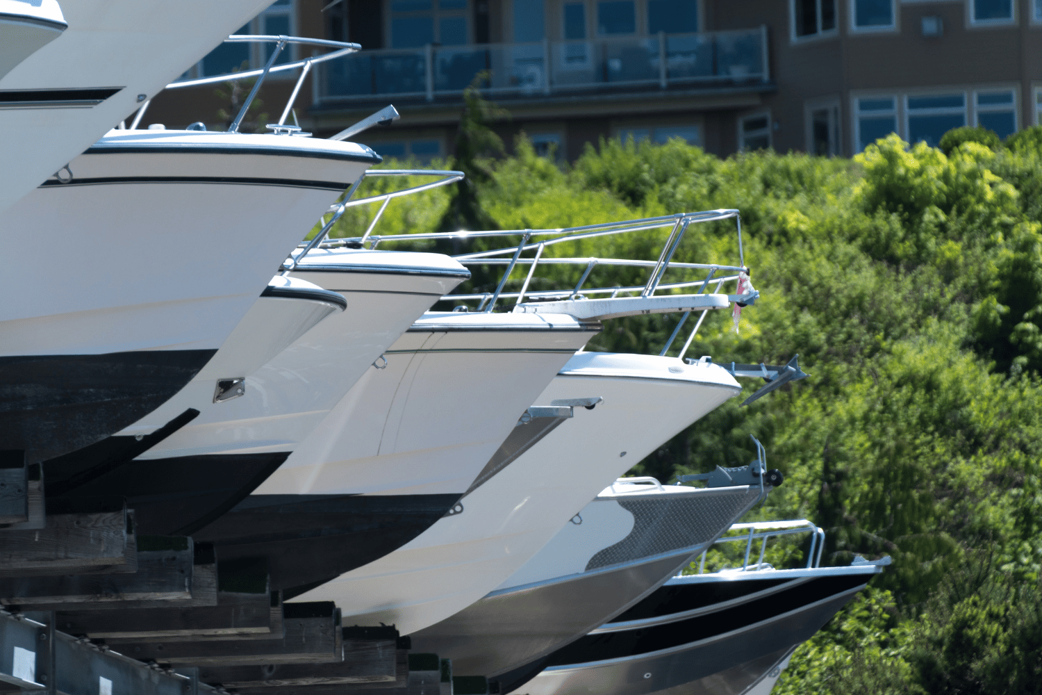 Several white yachts docked side by side with trees and a building in the background