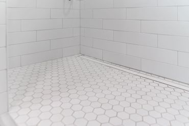 Empty white tiled corner with hexagon floor tiles and light gray brick walls. Empty white tiled corner with hexagon floor tiles and light gray brick walls.