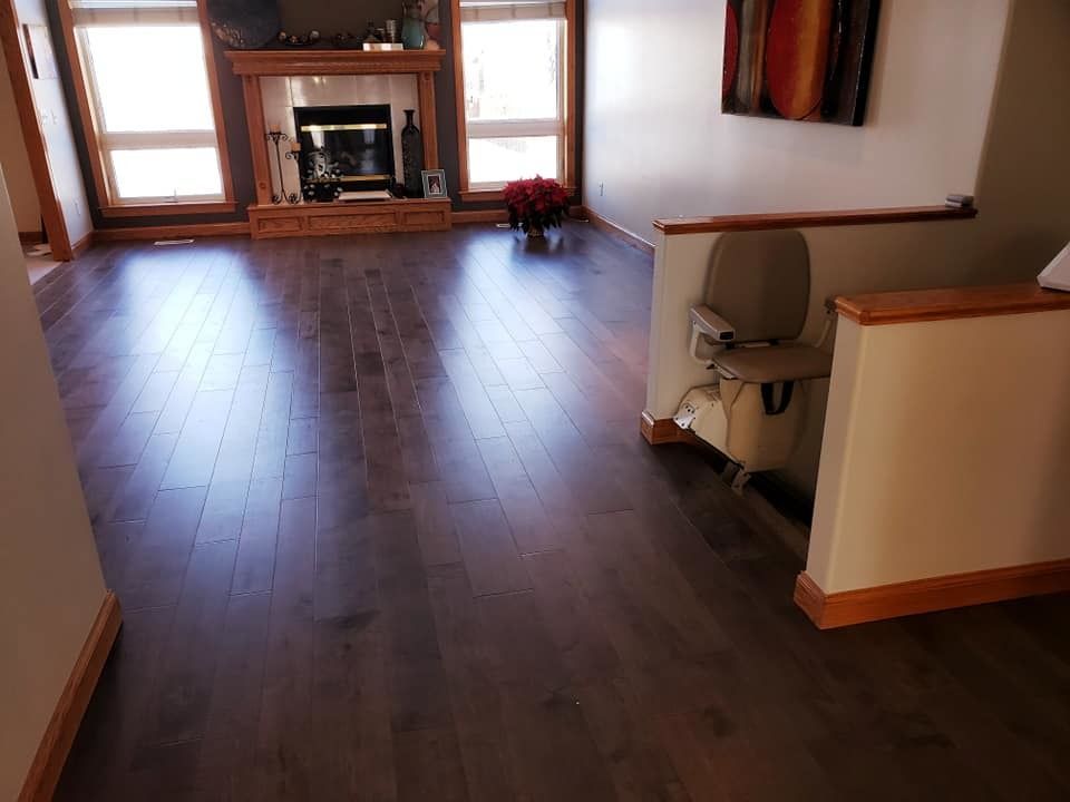 Empty living room with dark wood floors, fireplace, and sunlight from windows