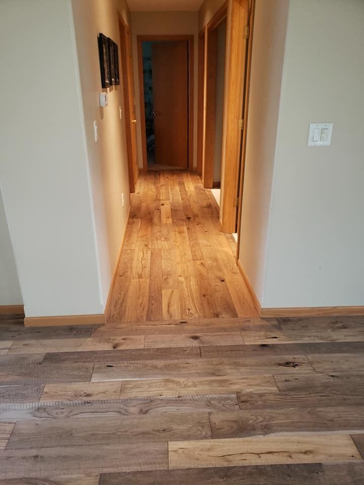 Wood-floored hallway with beige walls and doorways leading to a room and corridor.