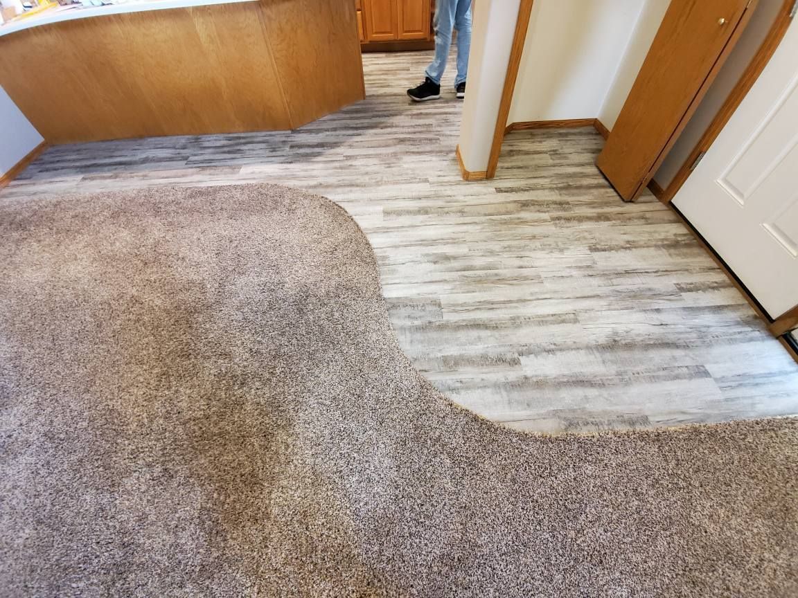 Carpeted floor with a large strip of damaged, bare flooring near a hallway and doorways