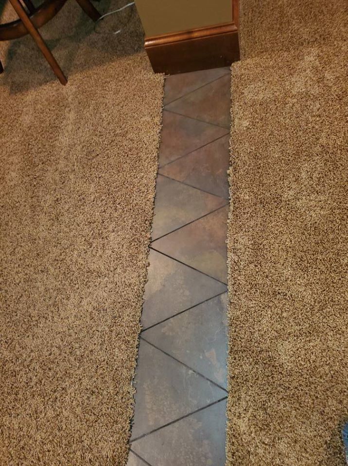 Narrow tiled walkway between tan carpeted areas in a home interior