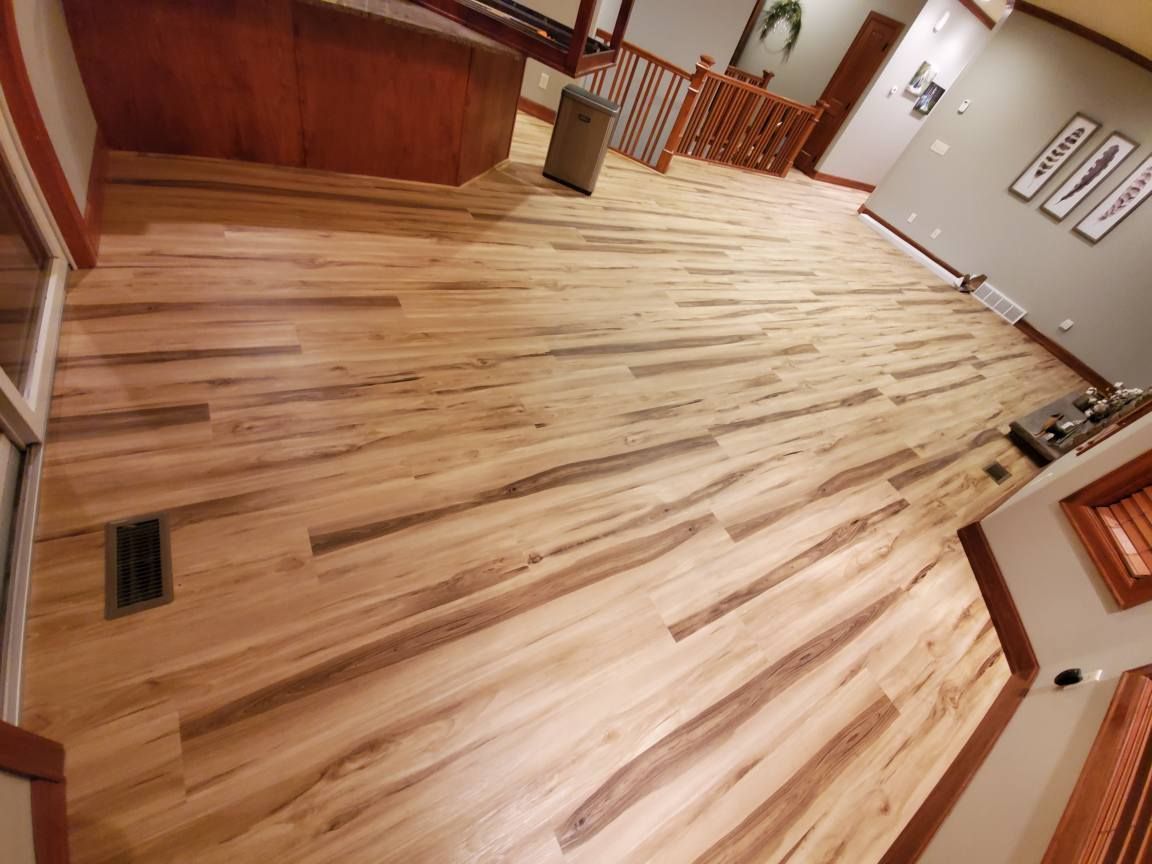 Empty hallway with new light wood flooring, wood railing, and gray walls in a building lobby