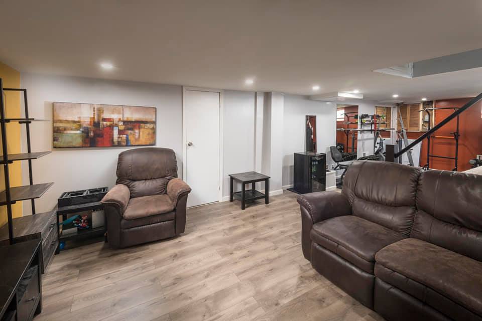 Living room with a brown leather couch and recliner, and wood flooring.