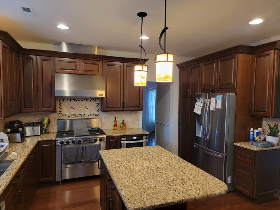 Brown kitchen with stainless steel appliances, granite countertops, and two pendant lights.