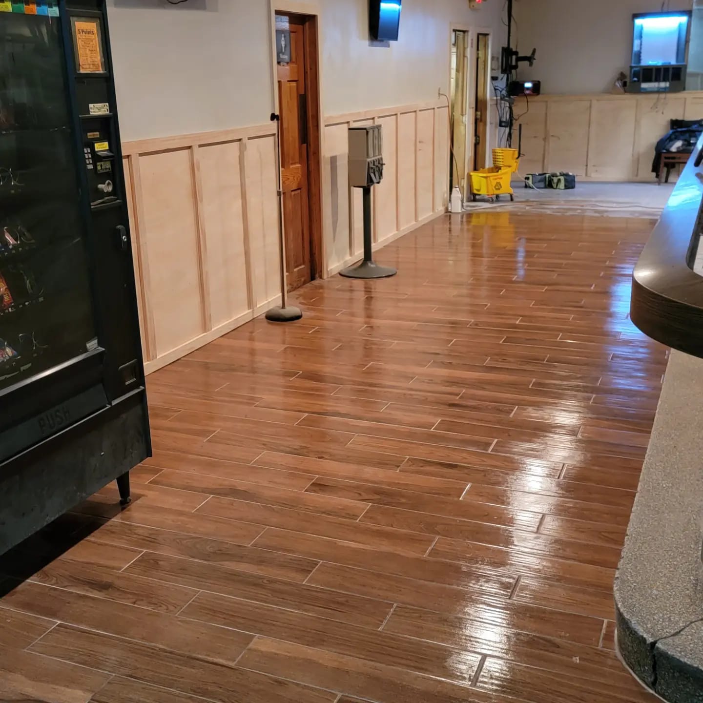 Wood-look floor in a commercial space, with vending machine, and hallway with a door.