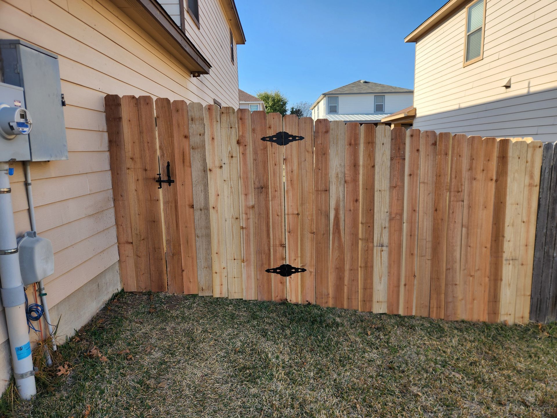 A wooden fence with a gate in the backyard of a house.
