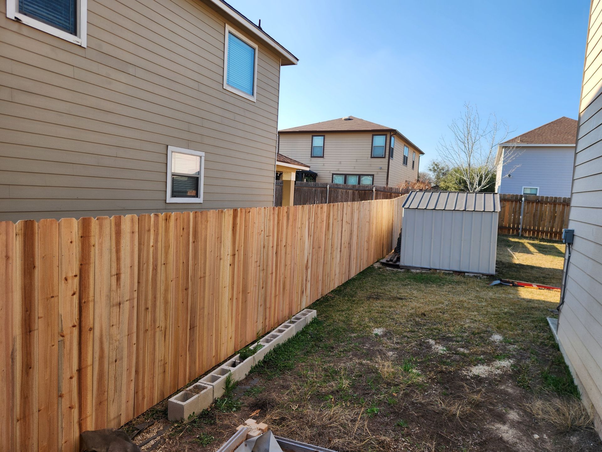 A wooden fence is in the backyard of a house.