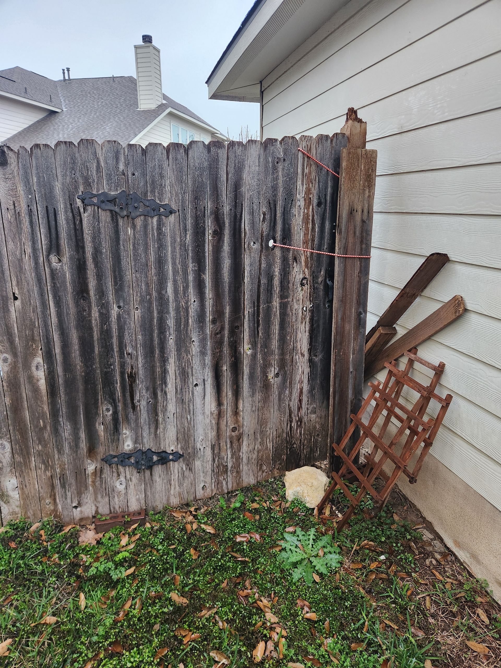 A wooden fence is sitting in the grass next to a house.
