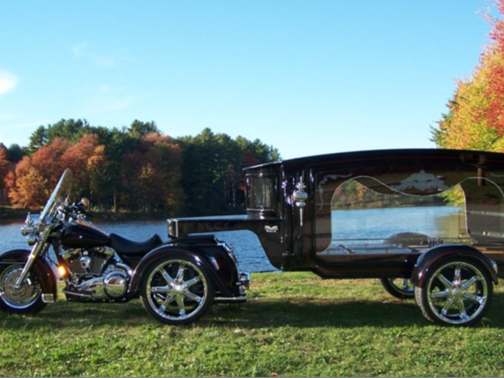A black motorcycle is parked next to a black hearse