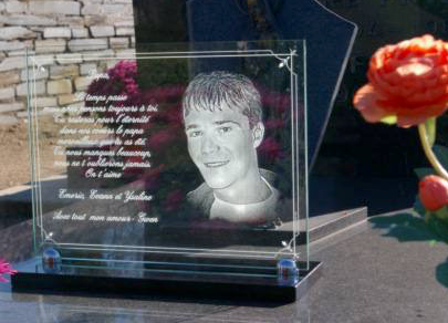 A plaque with a picture of a man on it is on a grave.