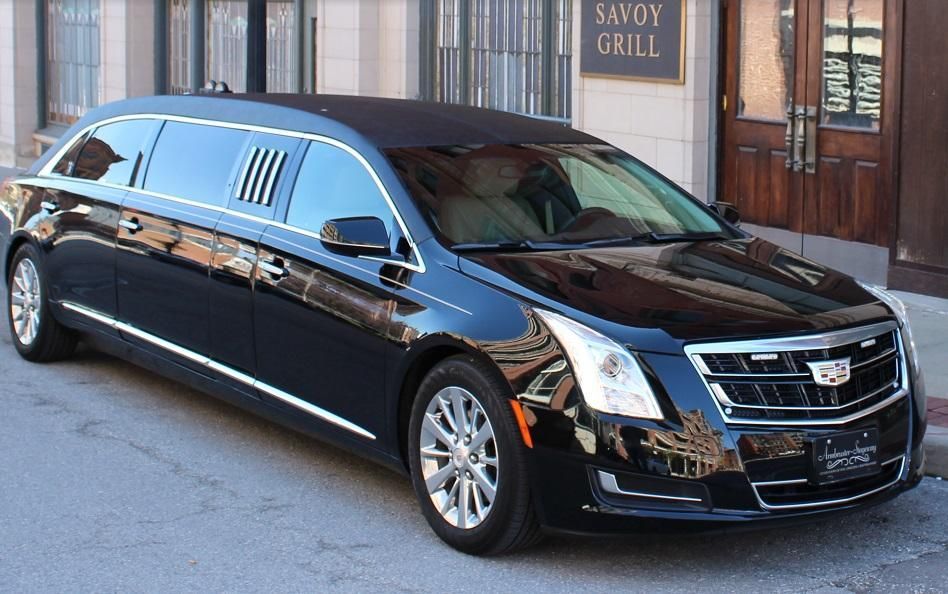 A black limousine is parked in front of a savoy grill