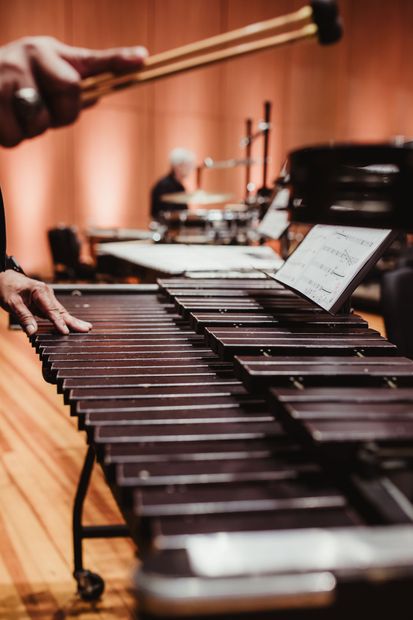 Percussionist striking marimba bars with a mallet on a concert stage