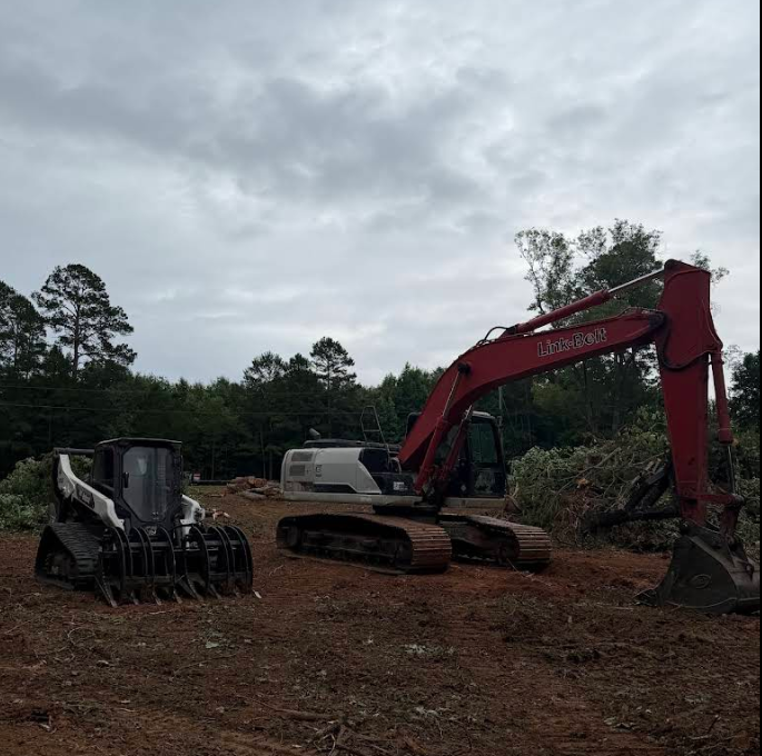 Yellow excavator digging into dark earth.