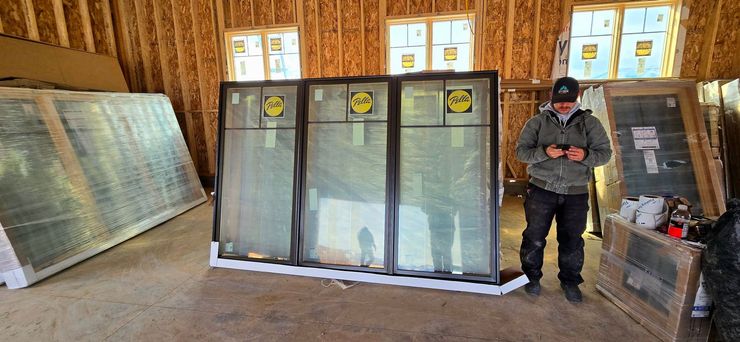 Person stands in a wooden shed beside large framed mesh panels and equipment boxes.