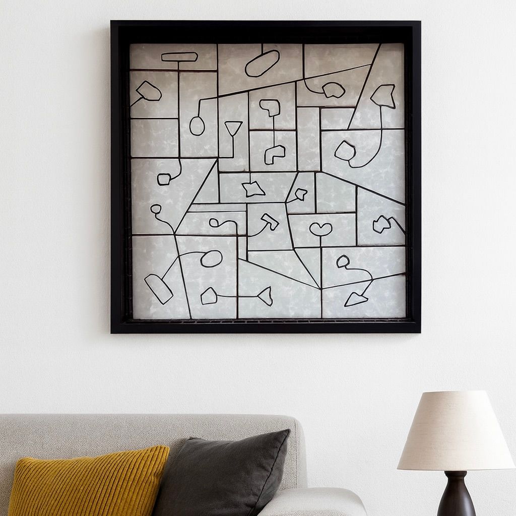 Abstracte wanddecoratie met zwarte lijst boven een grijze bank met mosterdgele en grijze kussens, naast een witte tafellamp.