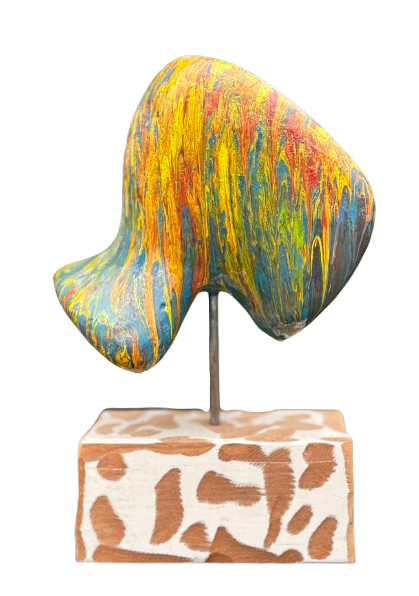 Abstracte, kleurrijke sculptuur op een sokkel boven een rechthoekige basis met patroon.