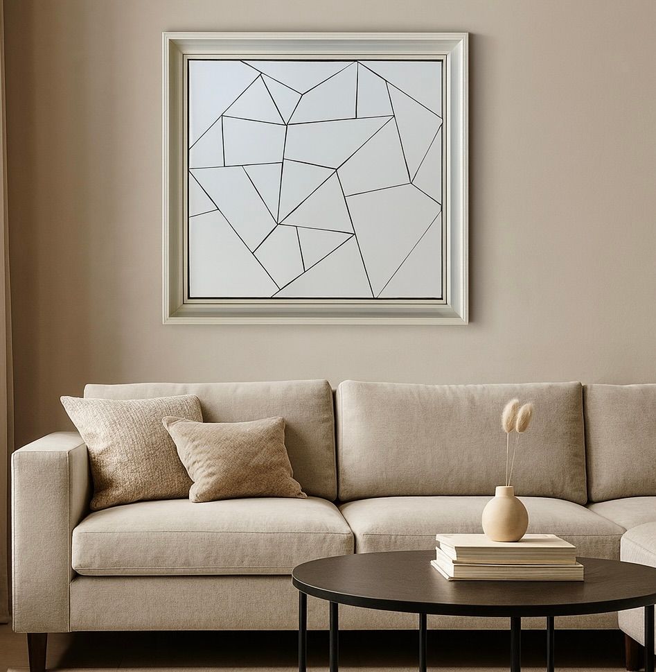 Moderne beige woonkamer met een hoekbank, ronde salontafel en abstracte ingelijste kunst aan de muur.