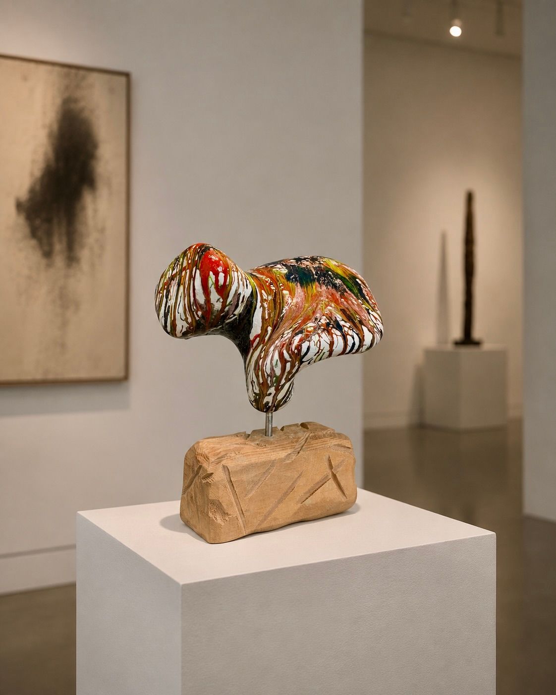 Abstracte, veelkleurige sculptuur op een witte sokkel in een kunstgalerie.