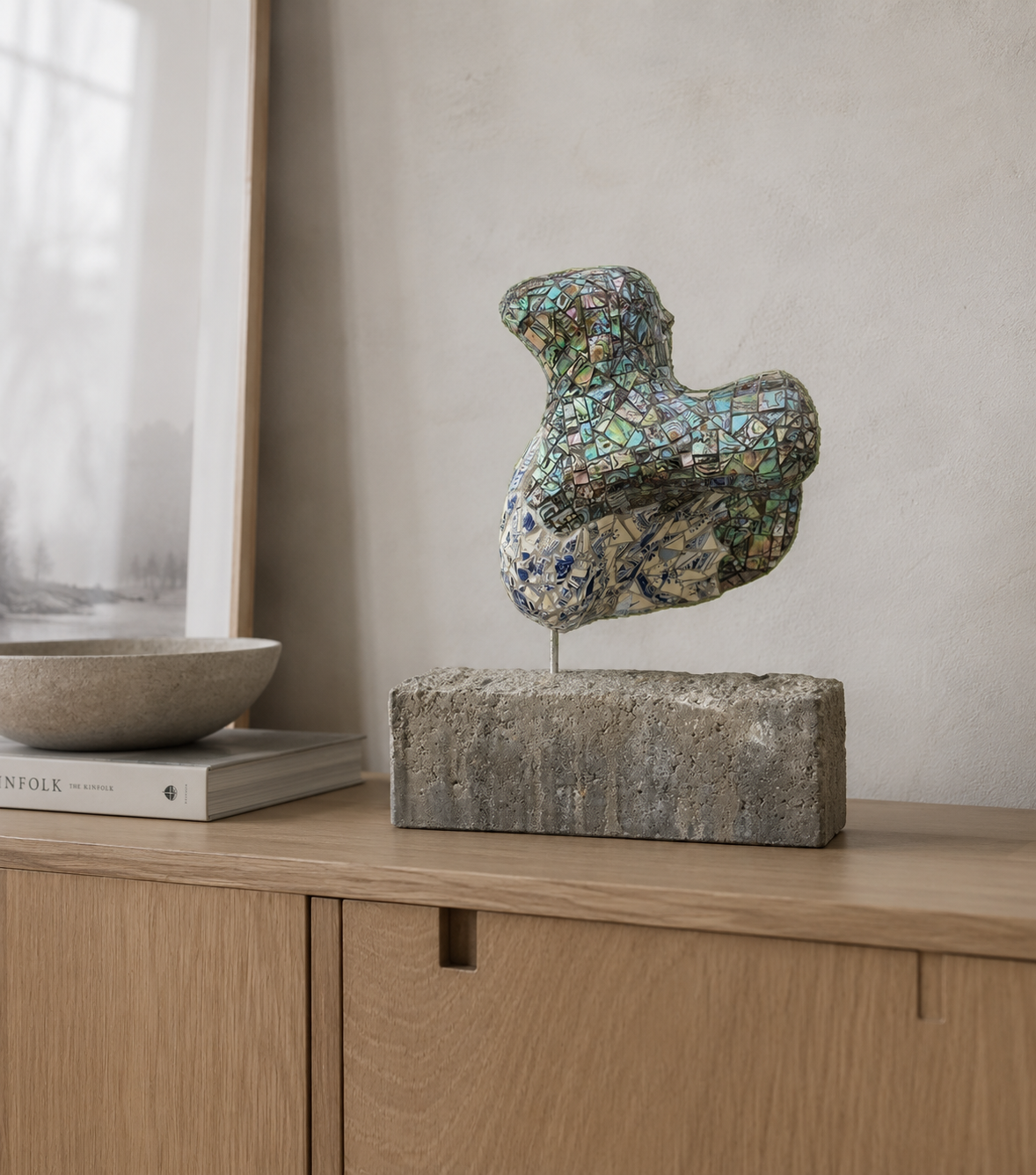 Mozaïek vogelsculptuur op een stenen sokkel bovenop een houten kast bij een raam.