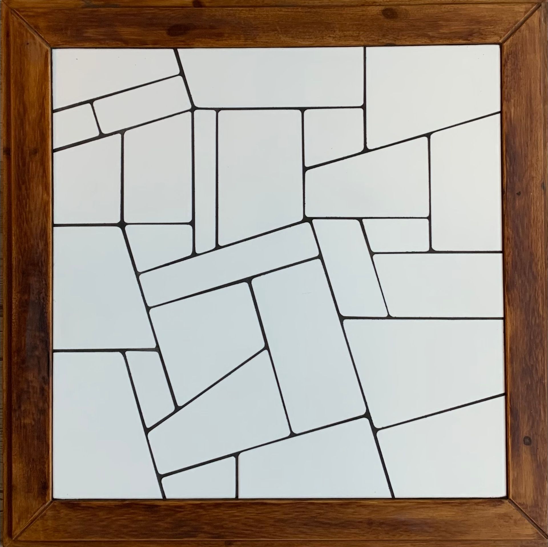 Abstracte geometrische puzzel met houten frame, bestaande uit onregelmatige witte tegels met een zwarte omlijning.