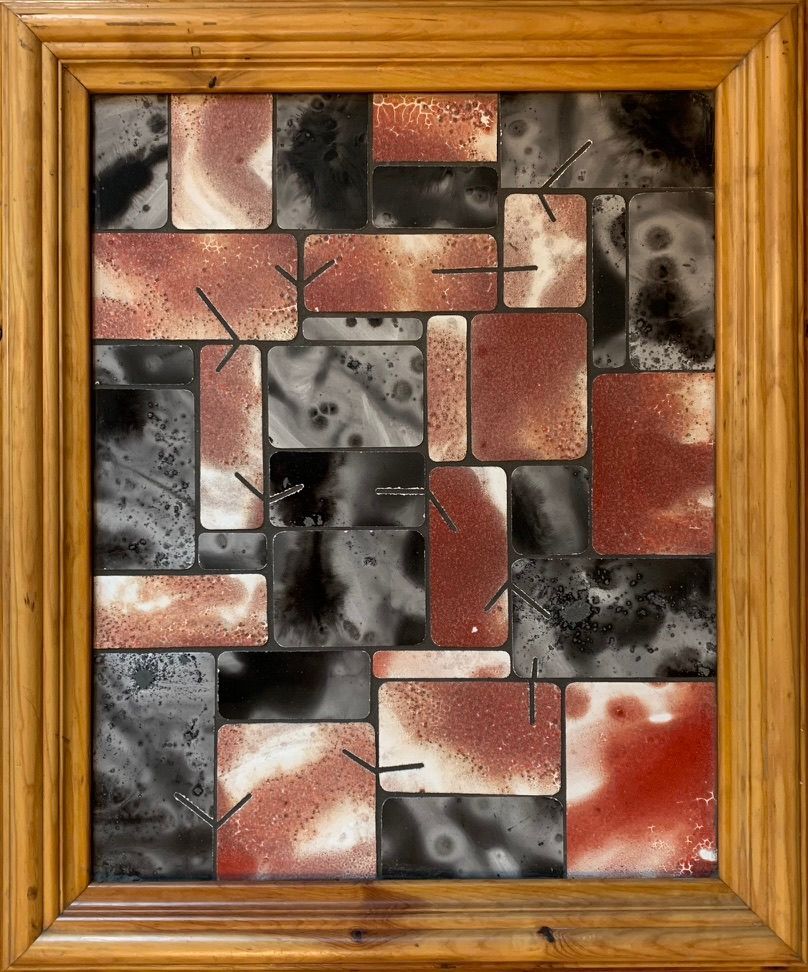 Abstracte mozaïek van zwarte, grijze en rode tegels in een houten frame.