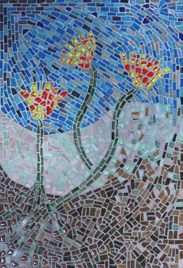 Mozaïek van drie rood-gele bloemen op hoge groene stengels tegen een blauw-grijze tegelachtergrond.