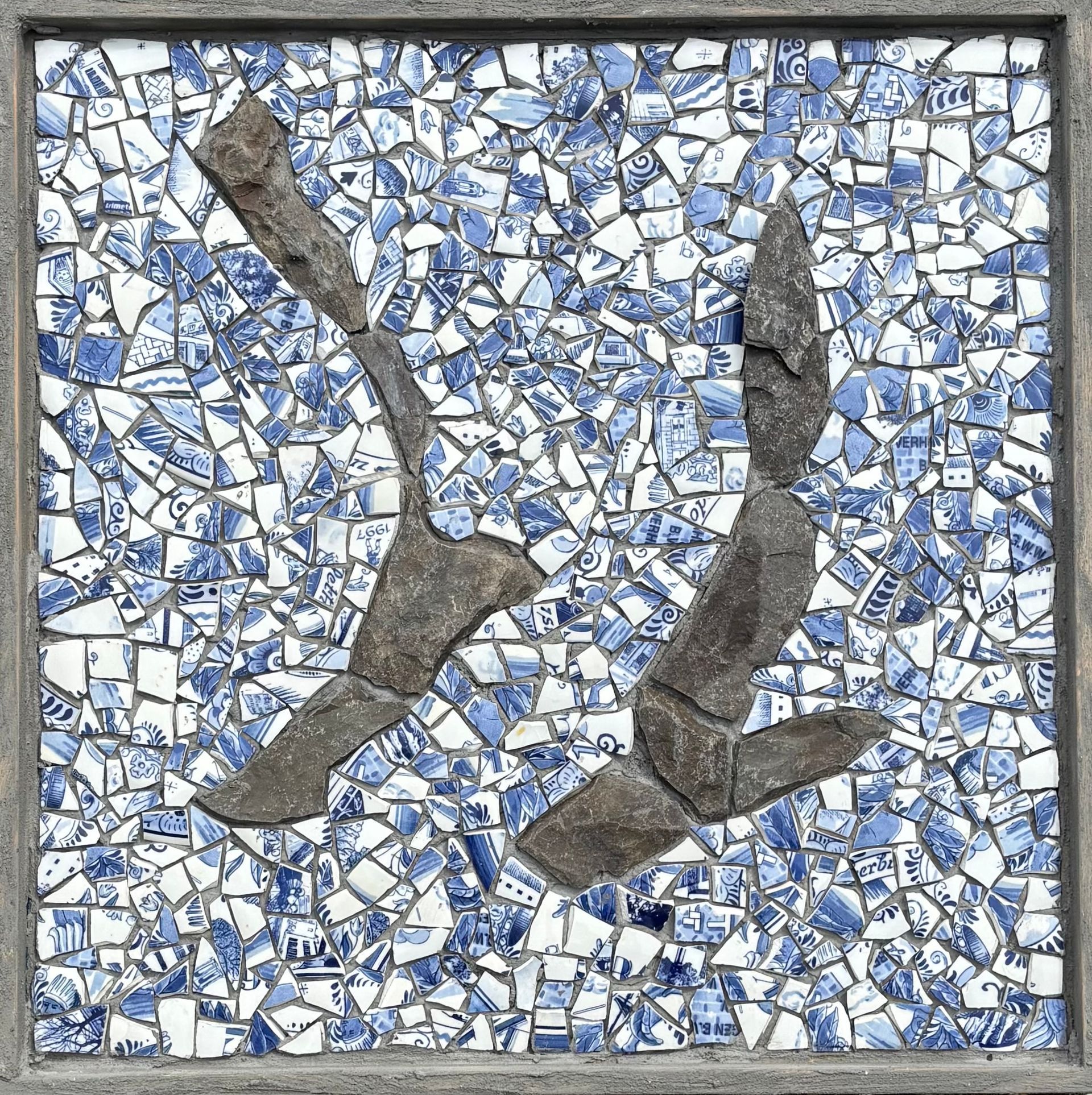 Abstracte mozaïek met blauw-witte tegels en twee donkere, gebogen vormen die een los Y-vormig patroon vormen.