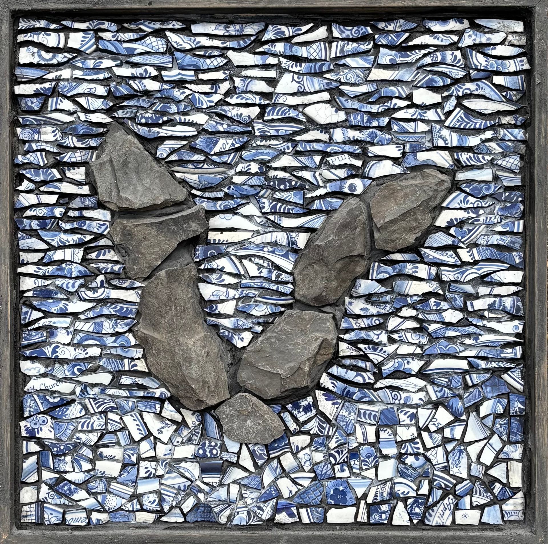 Mozaïek van een grijs, rotsachtig patroon op een blauw-witte stenen achtergrond.