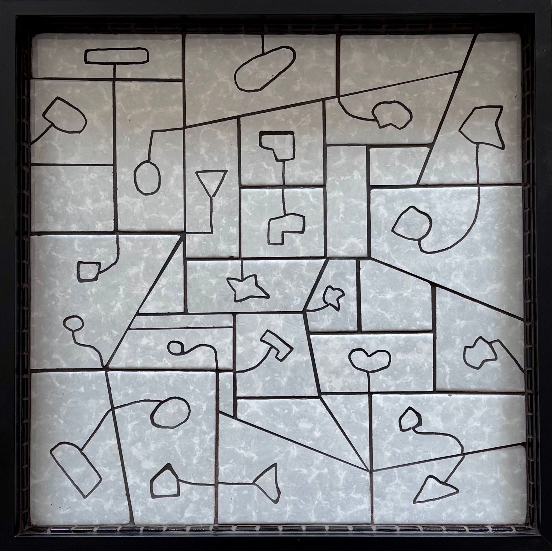 Abstracte mozaïek in zwart-wit van omlijnde vormen op een witte tegelondergrond, met kleine hartvormige symbolen ertussen.