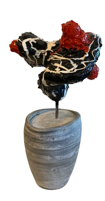 Abstracte sculptuur in zwart, wit en rood op een grijze sokkel tegen een witte achtergrond.