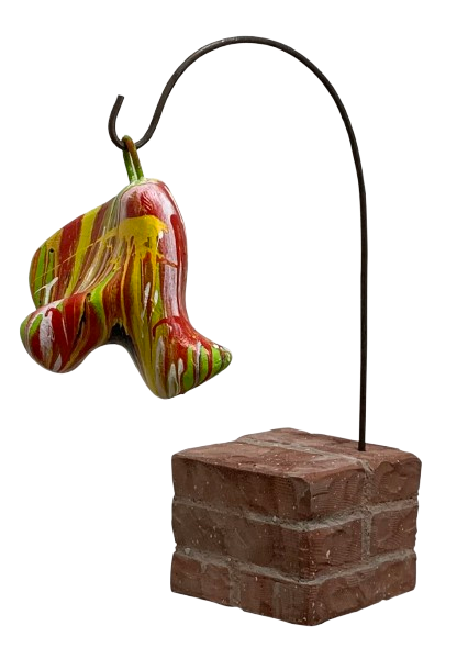 Abstract, kleurrijk, klokvormig ornament hangend aan een gebogen metalen standaard op een bakstenen voet.