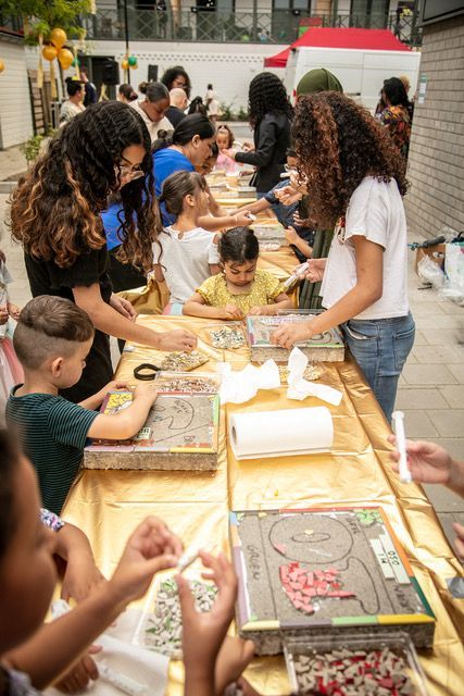 Mensen serveren taart aan een gemeenschappelijke tafel in de buitenlucht, omringd door kinderen.