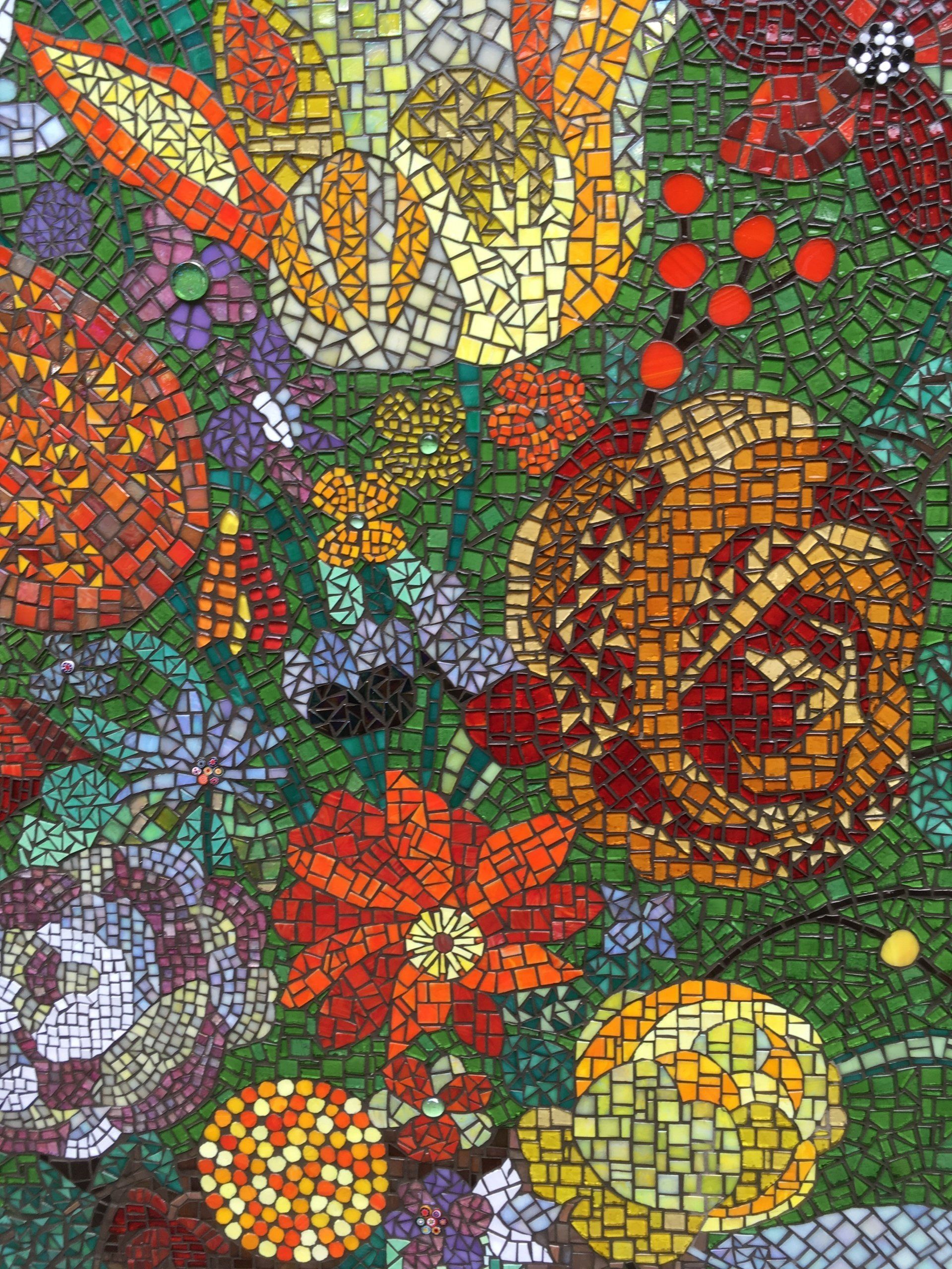 Een kleurrijk mozaïek van bloemen in rood, geel, paars en oranje met groene bladeren.