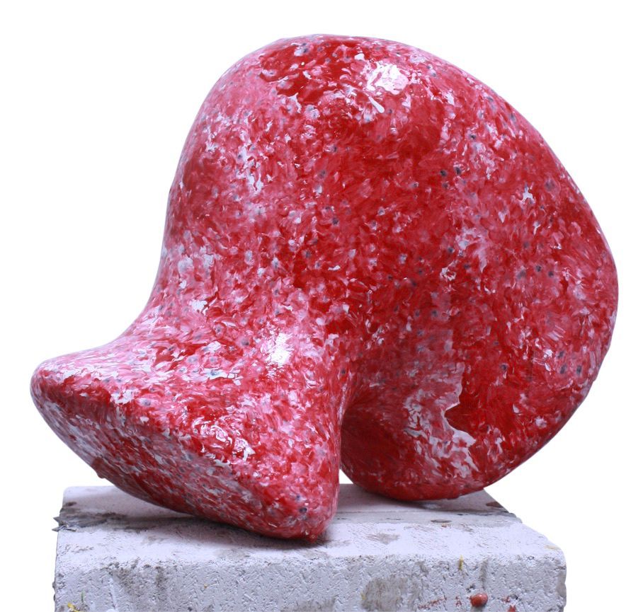 Abstracte rode sculptuur op een stenen sokkel, rood geschilderd met witte spikkels.